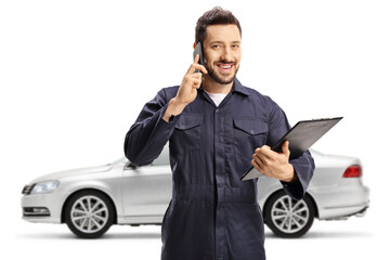 Auto mechanic worker talking on a mobile phone in front of a silver car