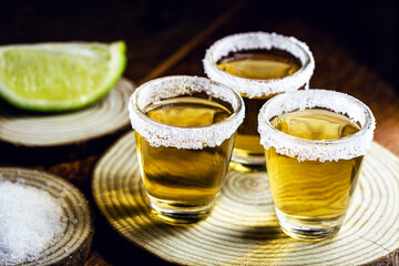 Tequila shot with lemon and sea salt on wooden background, selected focus
