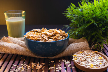 Desayuno saludable. Cereales en un bol azul acompañados de leche de avena sobre fondo de madera....