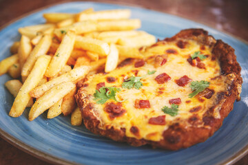 Milanese Gringacha with bbq sauce, gratin cheddar cheese and crispy bacon accompanied by french fries.