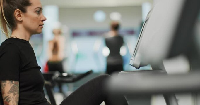 woman exercising with elliptical cross trainer at gym.Side view close-up, slow motion. Woman training at elliptical bike. Woman pedaling at gym
