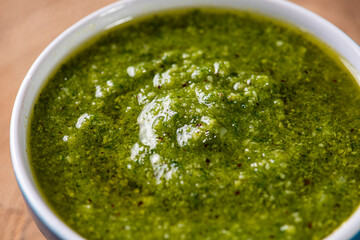 Pesto sauce in a bowl. On a wooden table. Selective focus. Top view. 