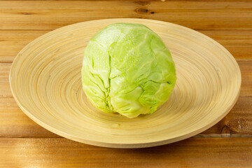 Bamboo plate with head of cabbage on wooden background