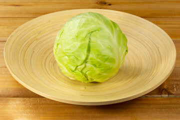 Bamboo plate with head of cabbage on wooden background