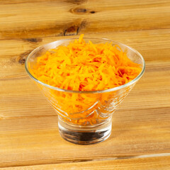 Grated carrots for salad or borsch in a glass vase on a wooden background