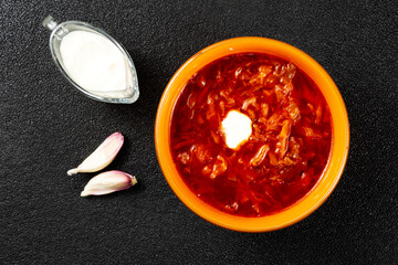 Traditional Ukrainian Russian borscht in the orange bowl. Plate of red beet root soup borsch on black rustick table. Beetroot soup.  Traditional Ukraine food cuisine. Top view
