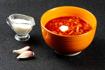 Traditional Ukrainian Russian borscht in the orange bowl. Plate of red beet root soup borsch on black rustick table. Beetroot soup.  Traditional Ukraine food cuisine