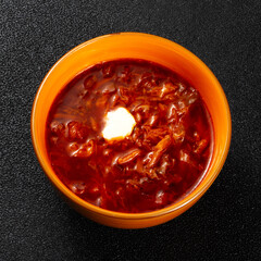 Traditional Ukrainian Russian borscht in the orange bowl. Plate of red beet root soup borsch on black rustick table. Beetroot soup.  Traditional Ukraine food cuisine