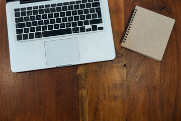 Laptop next to notebook, on aged wood background. teleworking concept. Confinement.