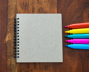 Notebook near colored markers on wooden table, drawing concept