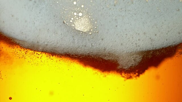 Super Slow Motion Detail Shot of Rippling Beer Bubbles and Foam in Glass at 1000fps.