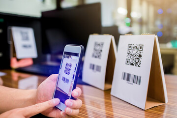 Closeup of a hand holding phone and scanning qr code. Man hand paying with qr code. Customer hand making payment through smart phone and scan code. Selective focus.