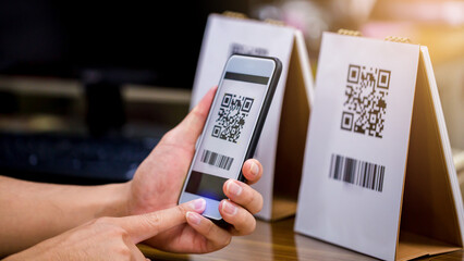 Closeup of a hand holding phone and scanning qr code. Man hand paying with qr code. Customer hand...