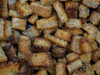 Selective focus on slices of fried rye bread close-up. Tasty ruddy rye croutons with vegetable oil and salt. Abstract food background.
