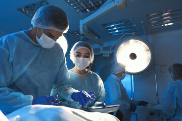 Team of professional doctors performing operation in surgery room