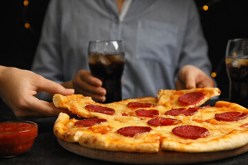 Women taking tasty pepperoni pizza at table, closeup