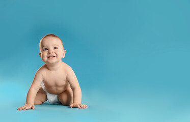 Cute little baby in diaper on light blue background. Space for text