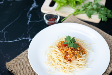 spaghetti with tomato sauce in a plate. black background. Close up.