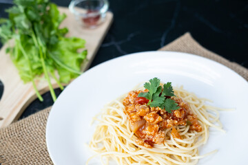 spaghetti with tomato sauce in a plate. black background. Close up.