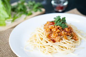 spaghetti with tomato sauce in a plate. black background. Close up.