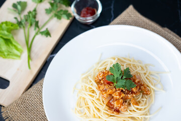 spaghetti with tomato sauce in a plate. black background. Close up.
