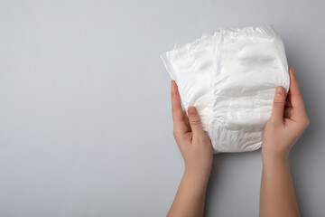 Woman with diapers on light grey background, closeup. Space for text - obrazy, fototapety, plakaty