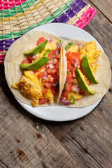 Breakfast egg tacos with flour tortilla and fresh sauce on wooden background