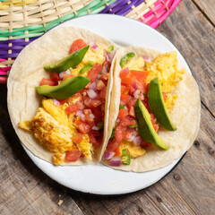 Breakfast egg tacos with flour tortilla and fresh sauce on wooden background