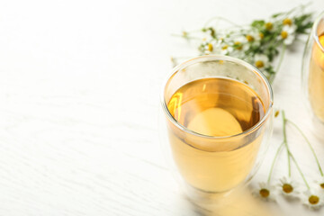 Delicious chamomile tea in glass on white table. Space for text