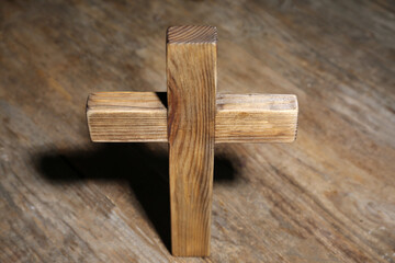 Christian cross on wooden background, above view. Religion concept