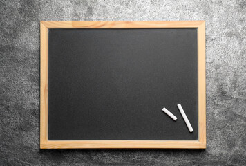 Empty blackboard with chalk on grey stone background, top view. Space for text