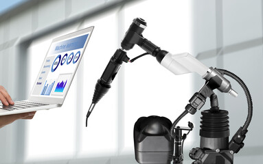 Engineer controlling electronic laboratory robot manipulator with laptop indoors, closeup. Machine...