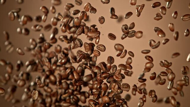 Super Slow Motion Shot of Crashing Coffee Beans on Brown Gradient Background at 1000fps.