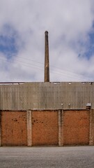 Vertical shot of a stone building with a brick funnel on the background