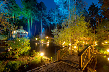 Fototapeta na wymiar Fairy tale cottages by the lake in the conifer forest at night