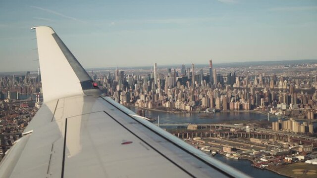 Looking out over a plane wing as a commercial flight departs New York City; densely populated Manhattan below.