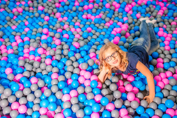 Fototapeta na wymiar Portrait of Playful Caucasian Teenager Girl Posing in Pool With Colorful Balls.