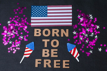 "Born to be free", phrase made from wooden letters, USA flag, fireworks and little stars on black background
