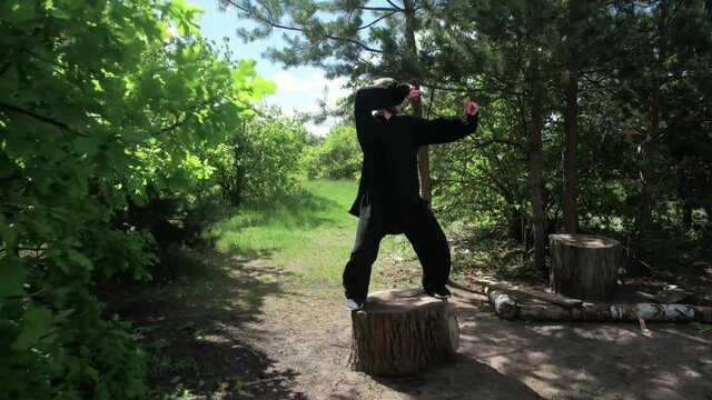 A man practices traditional Chinese kung fu gymnastics standing on a stump