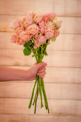 Women hand holding a bouquet of Sahara Sensation roses variety, studio shot, pink flowers