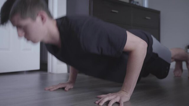 A young man doing pushups in his bedroom.
