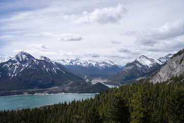 View on snowy mountain peaks and forest valley with lake, shot in Canadian Rockies at Prairie View Trail, Kananaskis, Alberta, Canada