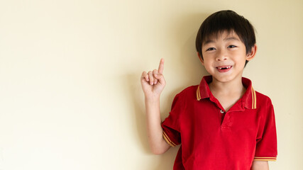 One  lovely Asian boy is pointing the finger up like presenting something or getting some idea. The smart and creative kid concept.