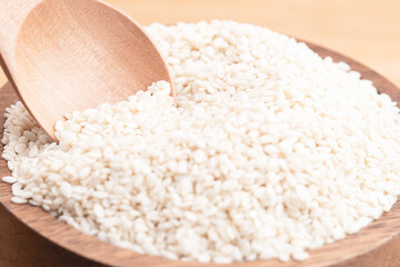 close up view of white sesame seeds in a wooden spoon