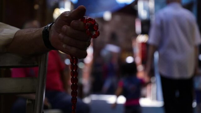 Old Caucasian man hand holding and manipulating worry beads to pass time sojourning, close up