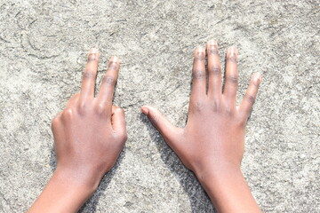 Hands holding up 7 fingers over grey concrete background