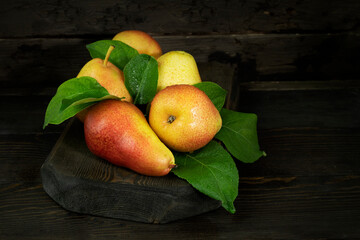 Ripe pear fruits and green leaves on a wooden table. Still life in the village style.