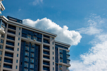 The upper part of a multi-storey residential building on a background of blue sky and clouds