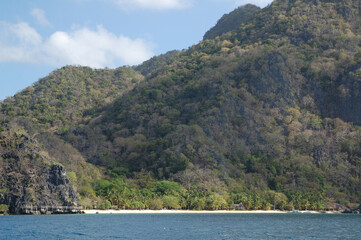 Limestone rock formation with sands, trees, and blue water sea