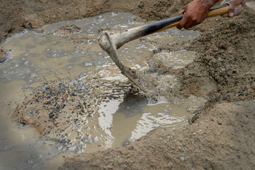 Indian labour mixing cement and water manually on floor using a shovel. Stock image.